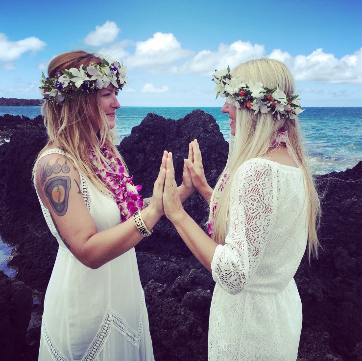 two brides pressing hands together and smiling